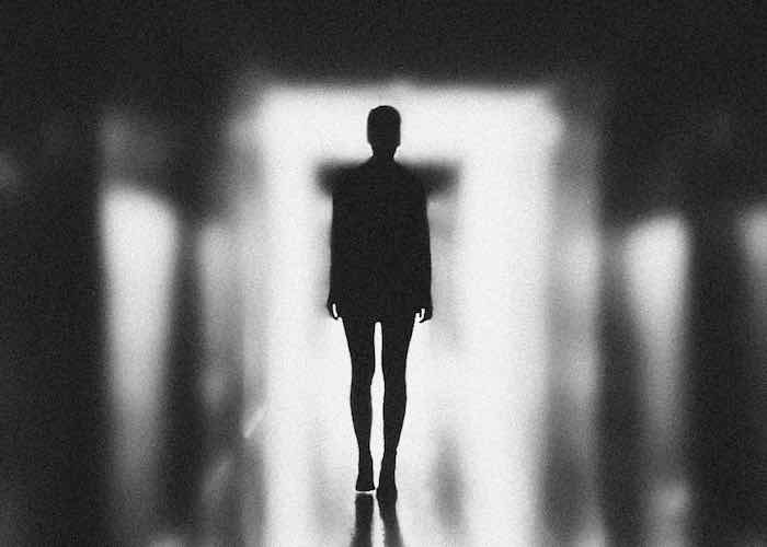 Ombra di donna in controluce che si
                                 avvicina nella stanza a passi lenti.